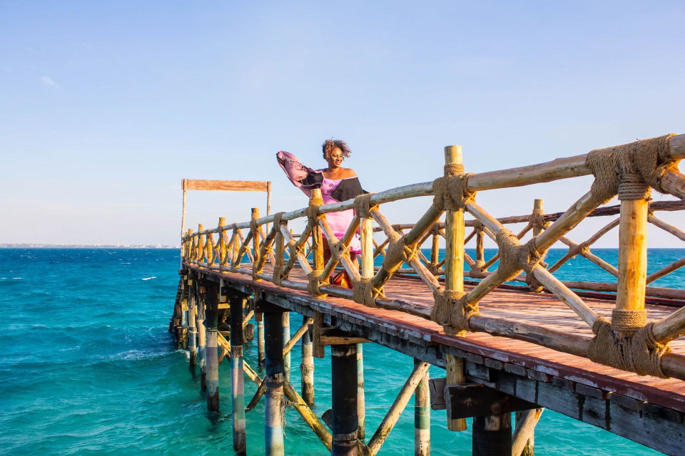 A lady stands on a dock during a windy day in Prison Island, Zanzibar