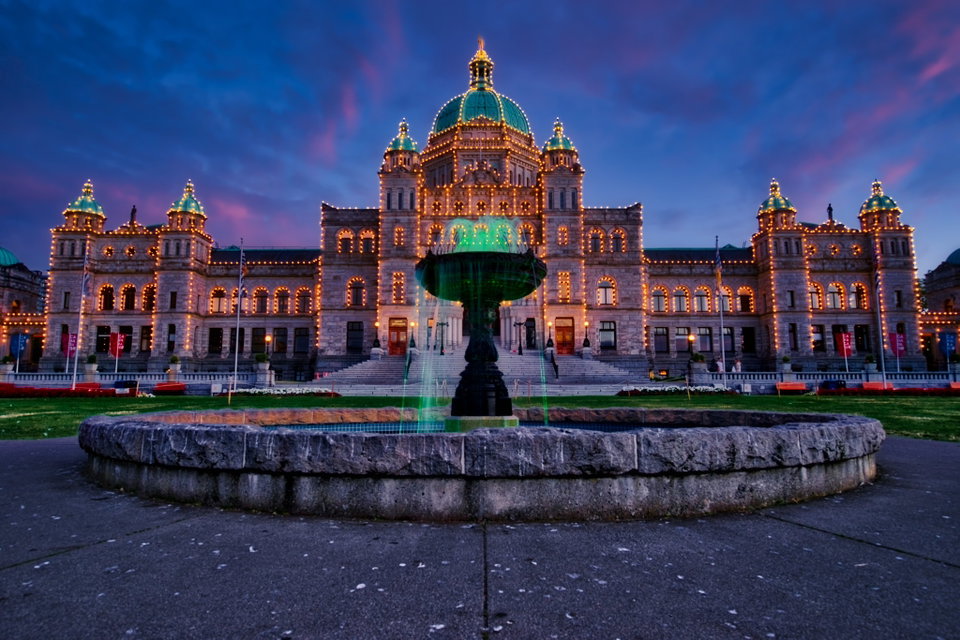 Victoria's Inner Harbour at dusk, with the illuminated Fairmont Empress Hotel and British Columbia Parliament Buildings reflected in calm water