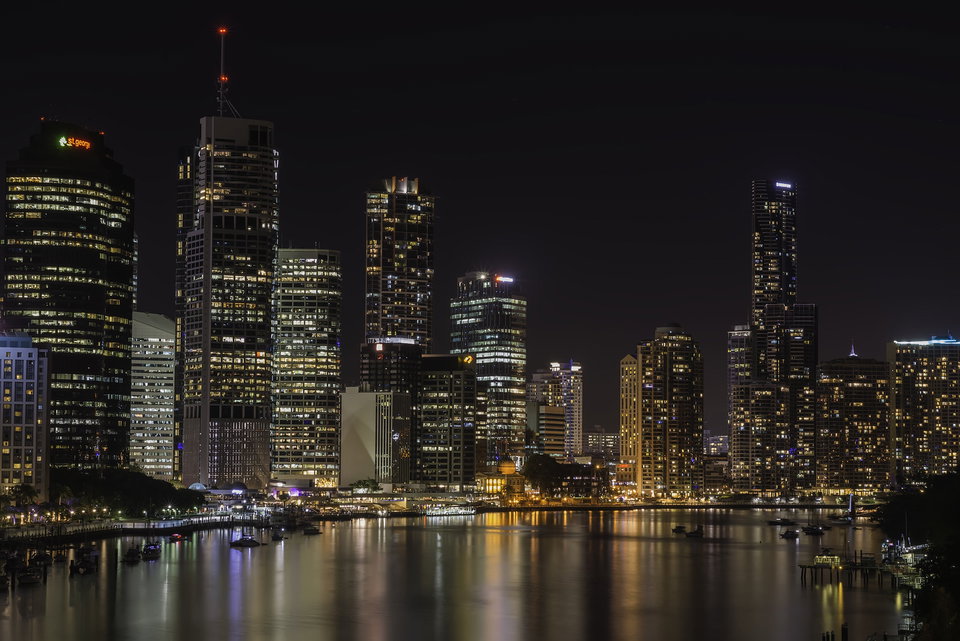 Brisbane city skyline reflected in the Brisbane River at dusk, with Story Bridge lit up in the background