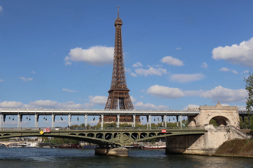 The Eiffel Tower at dusk rising above the Seine river with golden Parisian lights reflected on the water