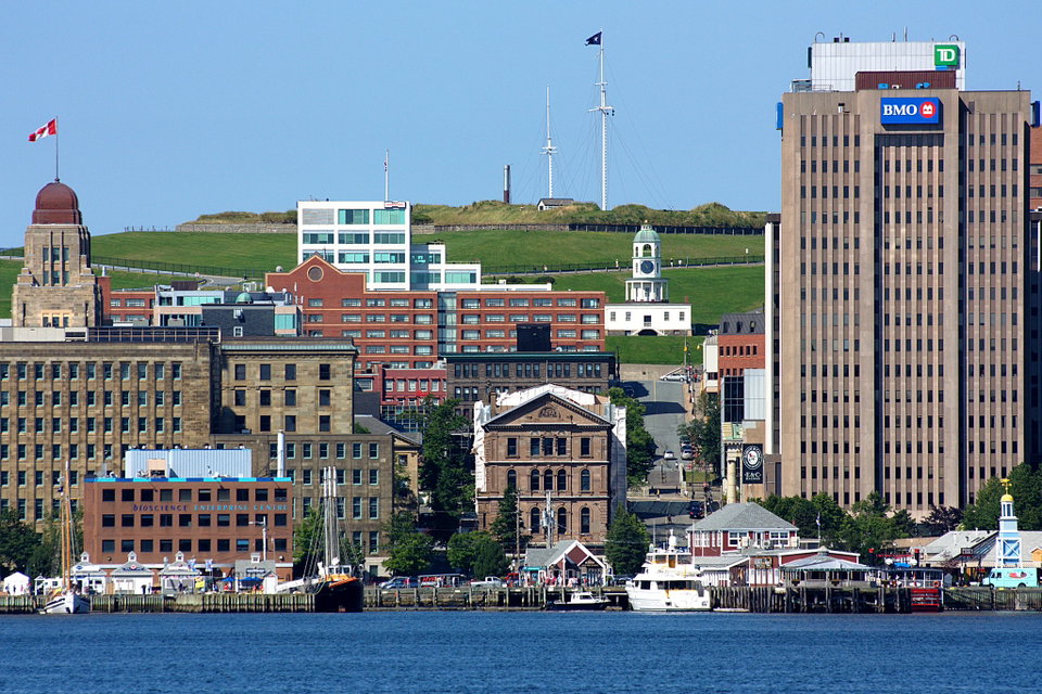 Halifax waterfront boardwalk at dusk with colourful historic buildings and sailing vessels reflected in the harbour