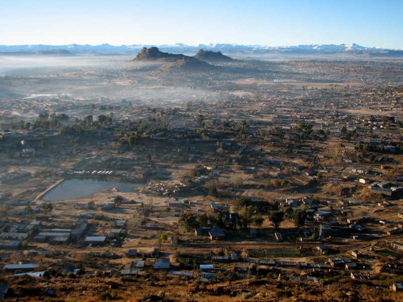 Maseru city skyline at dusk with the Maluti Mountains rising behind the rooftops