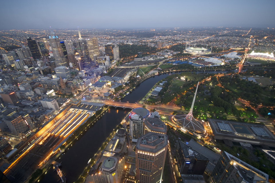 Melbourne city skyline reflected in the Yarra River at dusk, with the Southbank promenade lit up