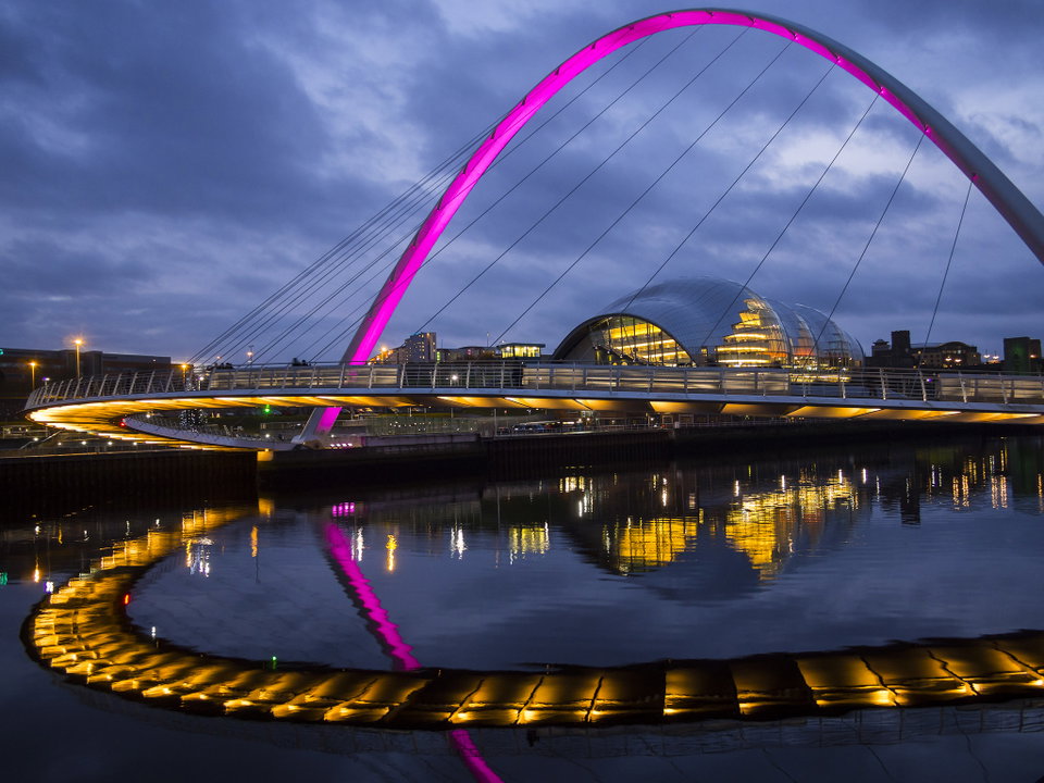 Newcastle upon Tyne skyline at dusk with the Tyne Bridge illuminated over the River Tyne