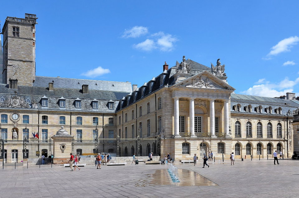 Golden-tiled rooftops and medieval spires of Dijon's old town under a clear blue sky
