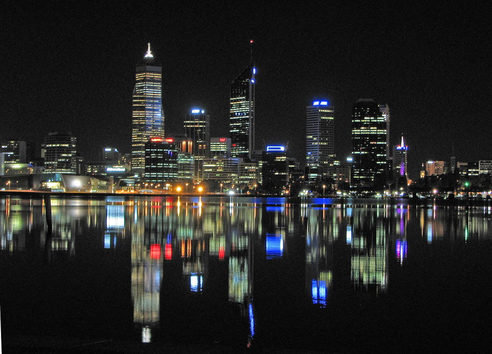 Perth city skyline reflected in the Swan River at sunset, with Kings Park in the foreground