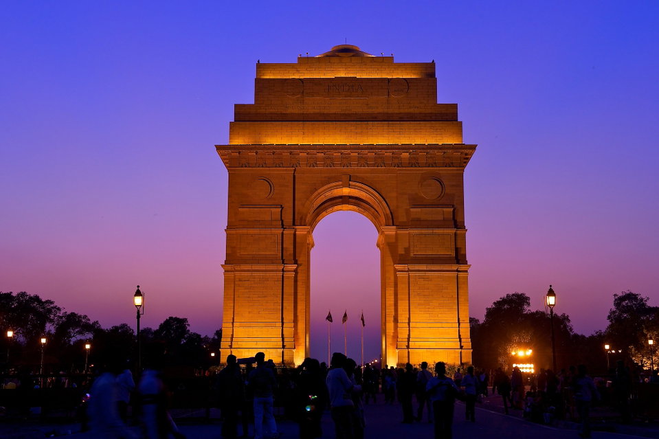 The iconic India Gate war memorial at dusk, framed by tree-lined Rajpath boulevard in New Delhi