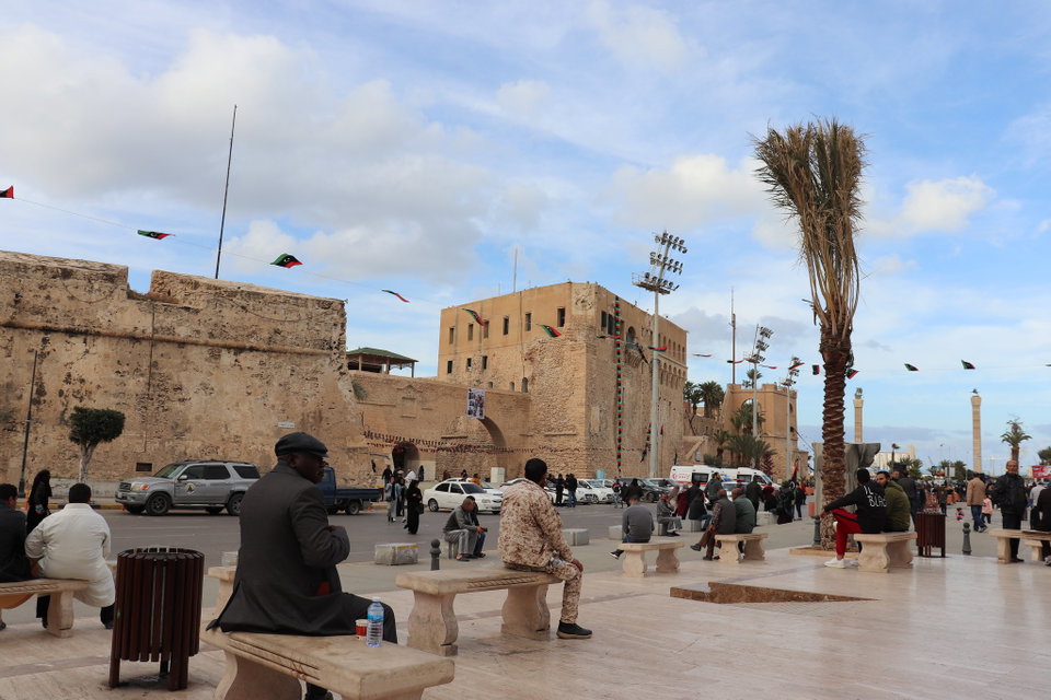 The arched arcades of the Medina of Tripoli at dusk, with the Red Castle silhouetted against an orange sky