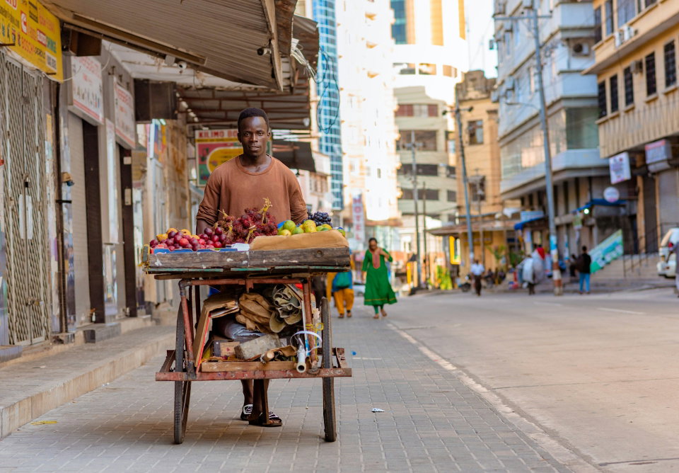 A street trader pushes his cart along a street in Dar es Salaam, Tanzania. Photo by Ali Mkumbwa.