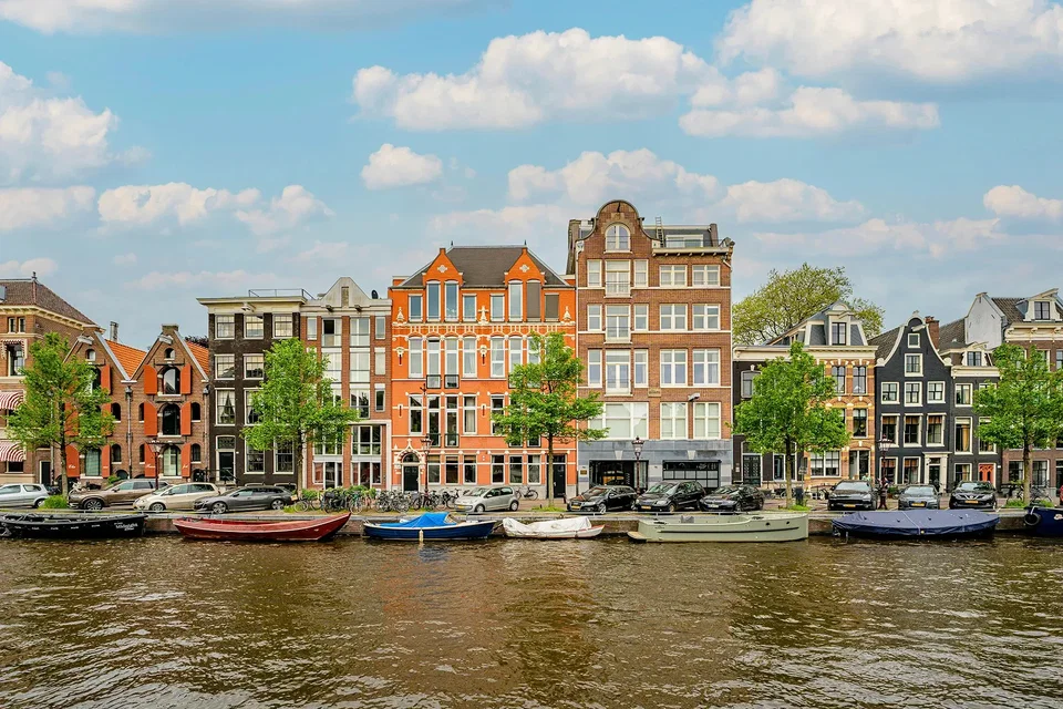 Amsterdam canal lined with narrow townhouses and bicycles at dusk