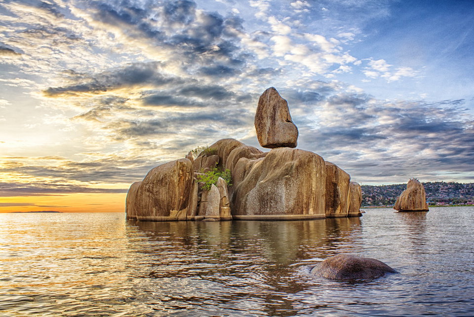 Sunset over Lake Victoria from Mwanza, with fishing boats silhouetted against an orange sky and Bismarck Rock in the distance