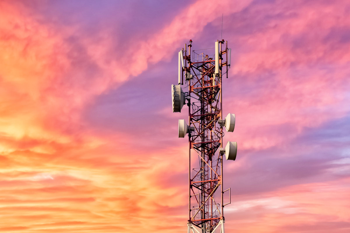 Telecommunications radio mast for cellphones against a colorful sky at sunset.