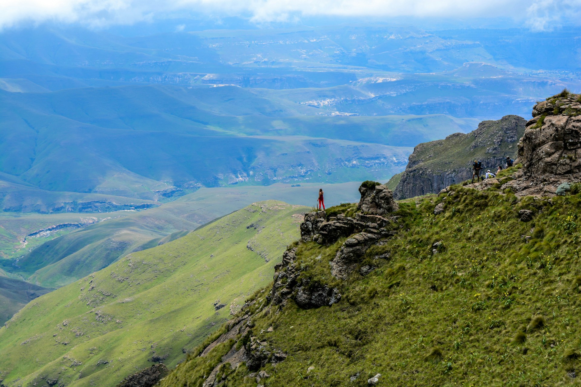 Woman on the edge of a mountain cliff. Drakensberg Mountains, South Africa. Photo by Dannii Coughlan.