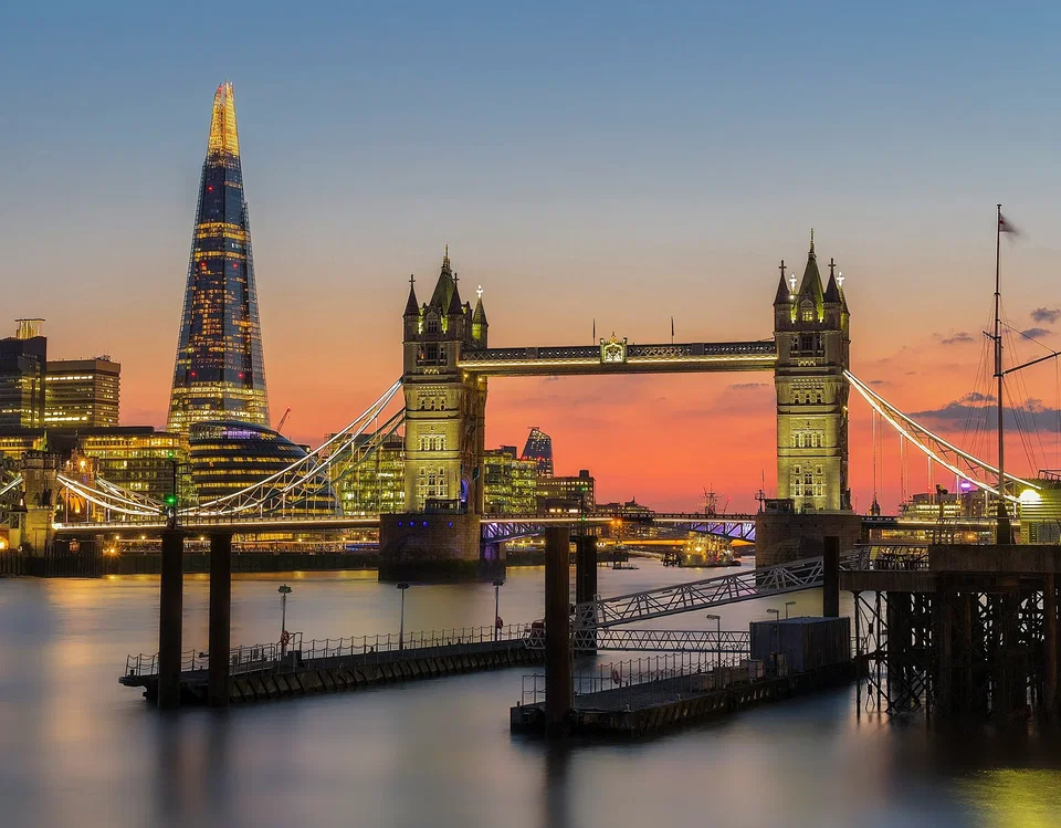 The River Thames at dusk with Tower Bridge illuminated and the City of London skyline in the background