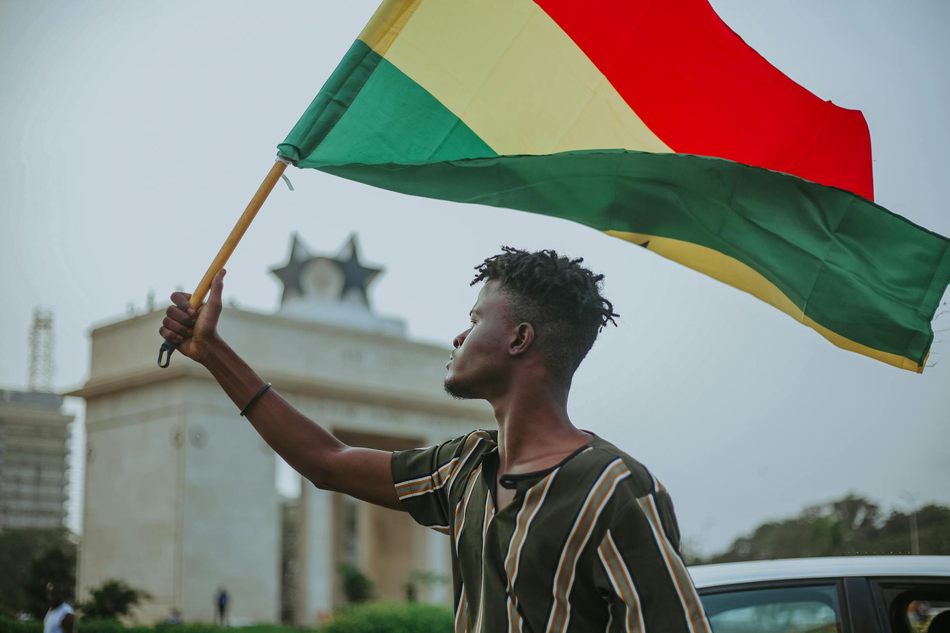 A man waves a flag along a street in Accra, Ghana. Photo by Asiama Junior.