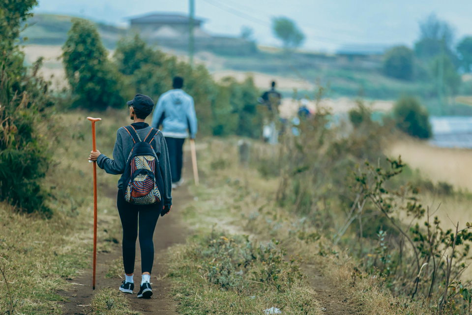 Hikers with backpacks and walking sticks explore a scenic outdoor trail. Photo by Chris wade Ntezicimpa.