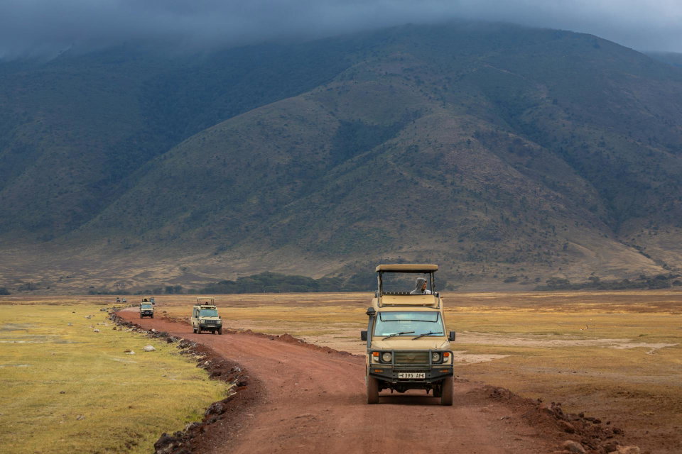 Safari vehicles on dusty road in Ngorongoro Crater. Photo by Sergey Guk.