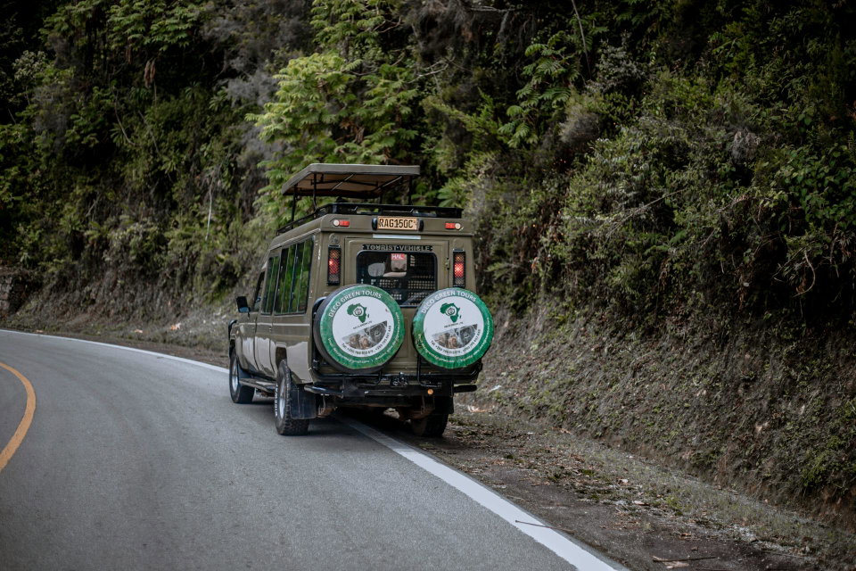 Safari tour van on a winding forest road in Rwanda. Photo by James Hassan.