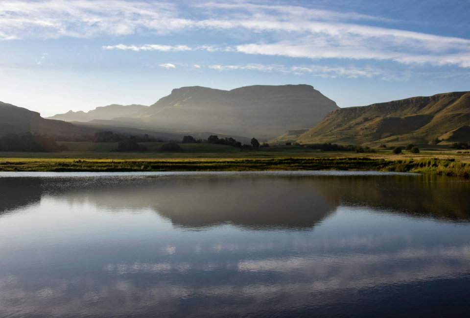 A lake near a mountain under a blue sky in Himeville, KZN, South Africa. Photo by Magda Ehlers.